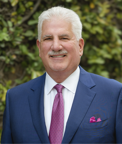 Portrait of Rodney Barreto, Chairman of the Florida Fish and Wildlife Conservation Commission, wearing a blue suit and pink tie outdoors.