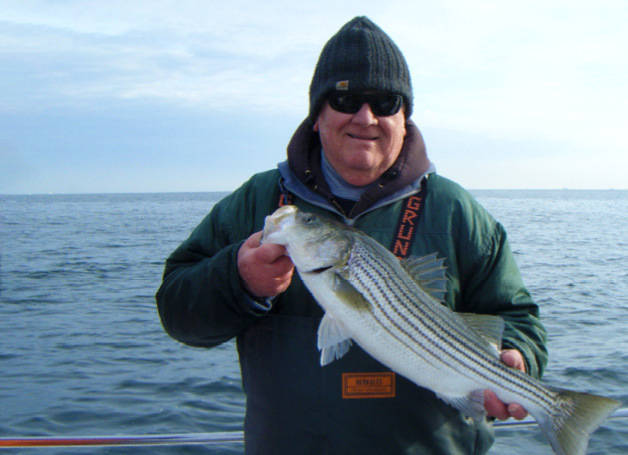 An angler holding a striped bass caught on the Susan Hudson off Barnegat Light, NJ.