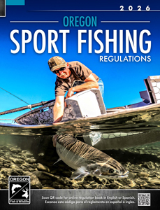 Cover of the 2026 Oregon Sport Fishing Regulations booklet showing an angler kneeling beside a boat in clear shallow water while releasing a large fish. The bright blue sky and rocky riverbed are visible beneath the surface.